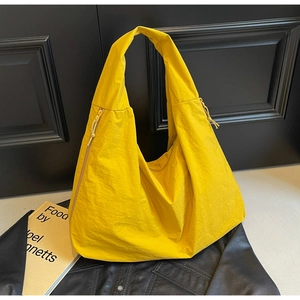 Detailed shot of yellow nylon tote bag with drawstring zipper on leather background