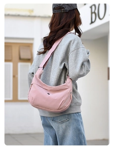 Pink nylon hobo bag shown from the side with wide adjustable strap for commuting