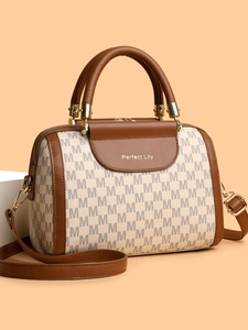 Detail of Boston bag featuring monogram print, brown leather flap, and golden hardware