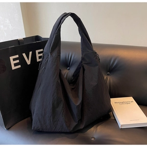 Close-up of black nylon tote bag on leather sofa showing water-resistant fabric texture