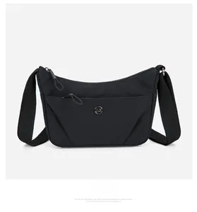 Détail du sac bandoulière en nylon noir avec poche zippée et logo métallique rond argenté