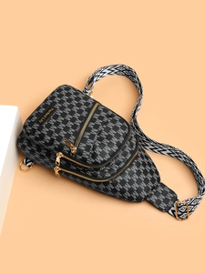 Detail of crossbody bag with grey M-letter pattern, golden zippers, and woven strap