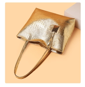 Detailopname van gouden krokodillenreliëf en metalen accenten op deze luxe tote bag