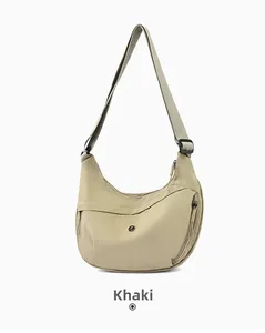 Detail of khaki crescent crossbody bag with adjustable strap and zip pocket