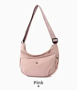 Detail of pink canvas hobo bag featuring a round metal logo and adjustable wide strap