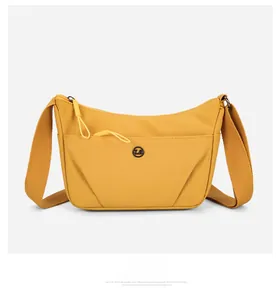 Détail frontal du sac bandoulière en nylon jaune avec fermeture éclair et logo métal