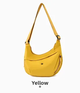 Detail of yellow nylon crescent crossbody bag featuring an adjustable strap and round logo