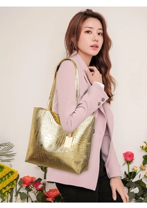 Detail van gouden tote tas met krokodillenpatroon en metallic textuur gedragen door model