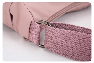 Détail du sac bandoulière en nylon rose montrant l'anneau métallique et la sangle tissée