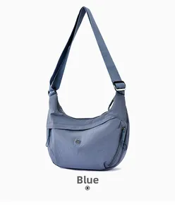 Close-up of blue nylon crescent bag featuring a metallic logo and adjustable strap