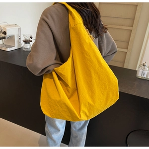 Detail of a yellow canvas tote bag with pleated fabric shown in a cafe setting