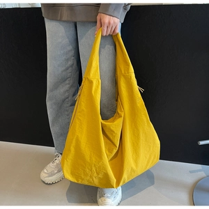Macro detail of vibrant yellow nylon tote bag featuring unique drawstring side texture