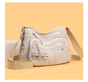 Detail of beige nylon crossbody bag with multi-zipper pockets and adjustable wide strap