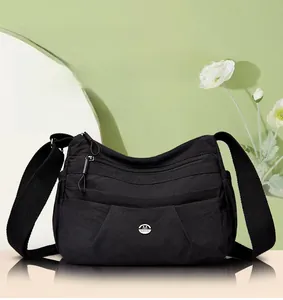 Detail view showing multi-layer zipper compartments and logo on the black nylon crossbody bag