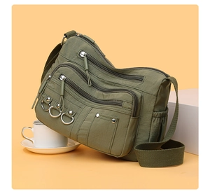 Detail of army green nylon crossbody bag with multiple zippers and adjustable strap