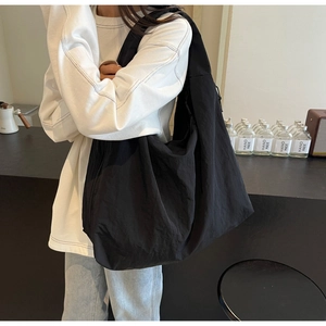 Detailed side view of a black large capacity canvas tote bag with wide shoulder strap