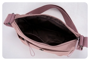 Vue détaillée des compartiments intérieurs spacieux du sac bandoulière en nylon rose