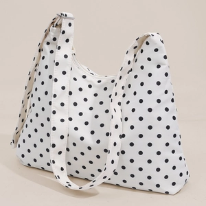 White hobo shoulder bag with black polka dots and adjustable wide strap, 45-degree view