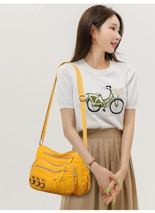 Detail of crossbody bag in ginger yellow featuring multiple functional zip pockets