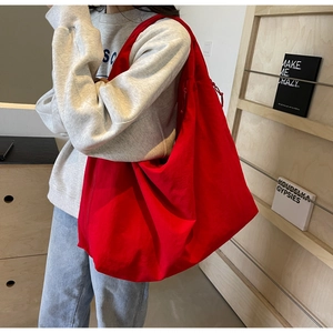 Large red canvas tote bag shown worn on shoulder for commuting and daily use