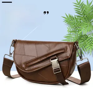 Detail view of brown saddle bag featuring contrast stitching and wide woven strap