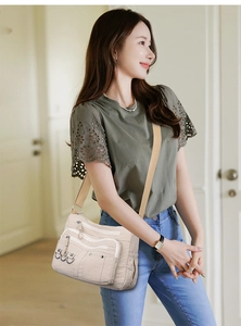 Detail of multi-pocket nylon crossbody bag with silver ring accents and adjustable strap