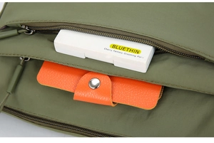 Detailansicht der olivgrünen Nylontasche mit orangefarbener Schnalle und Reißverschluss