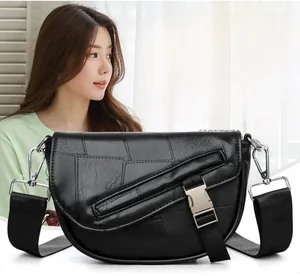 Detail of black crescent crossbody bag featuring silver buckle and wide strap