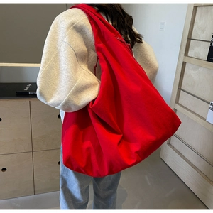 Detail of red slouchy canvas tote bag showing its large capacity and soft texture on model