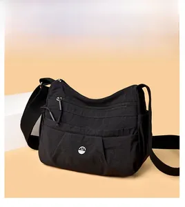 Detail of black nylon crossbody bag featuring multiple zipper pockets and metal M logo