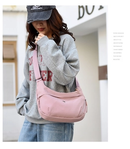 Close-up of pink nylon crescent bag with adjustable wide strap shown on a model outdoors