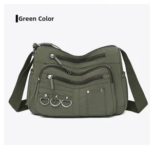 Close-up of army green nylon crossbody bag with multi-zipper pockets and silver rings