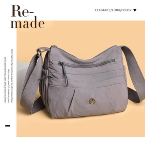 Detailed view of grey nylon crossbody bag with multiple zip pockets and wide shoulder strap