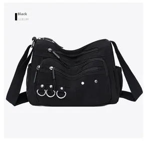 Close-up of black textured nylon crossbody bag featuring three functional zip pockets