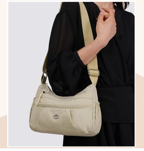 Detail of multi-pocket nylon crossbody bag with silver hardware and adjustable strap