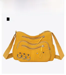Front view of yellow multi-pocket nylon crossbody bag with stylish silver ring accents