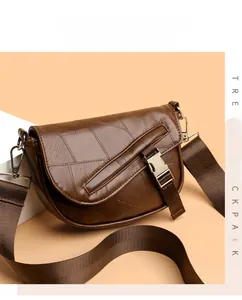 Close-up of brown saddle bag with litchi texture and adjustable nylon shoulder strap