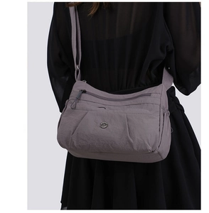 Detail view of purple waterproof nylon crossbody bag with multi-layer zipper compartments