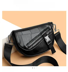 Detail of black saddle bag with textured patchwork, matte leather, and silver metal buckle