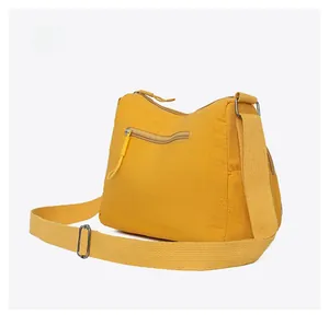 Detail view of bright yellow crossbody bag showing back zipper pocket and wide strap