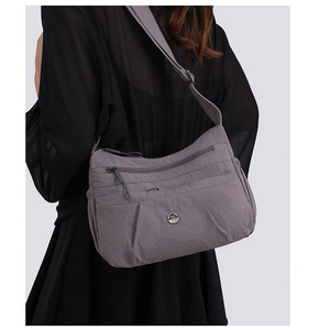 Detail of grey nylon crossbody bag with multi-layer zipper pockets and metallic M logo