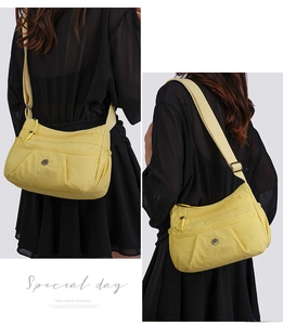 Detail of a bright yellow nylon crossbody bag featuring multiple zipper pockets and wide strap