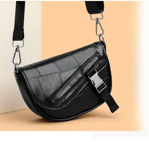Detail of black geometric patchwork saddle bag featuring a silver metal buckle closure