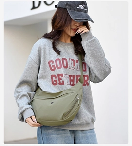 Outdoor shot of a matcha green nylon crescent bag worn by a model in a casual setting