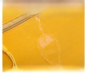 Close-up of bright yellow waterproof nylon fabric with water droplets on surface