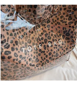 Detail of leopard print tote bag with transparent PVC outer layer and white text