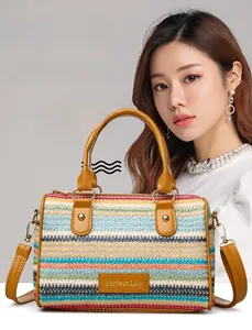 Detail of colorful woven straw bag featuring brown leather handles and gold metal logo