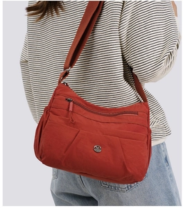 Detail of burnt orange nylon crossbody bag featuring multi-pocket design and adjustable strap