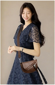 Brown leather crescent crossbody bag with flap metal buckle and wide woven shoulder strap