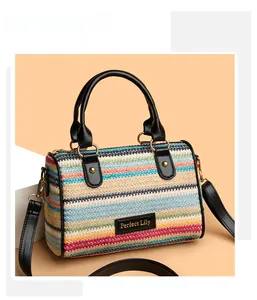 Detail of colorful striped woven Boston bag featuring black leather trim and gold hardware
